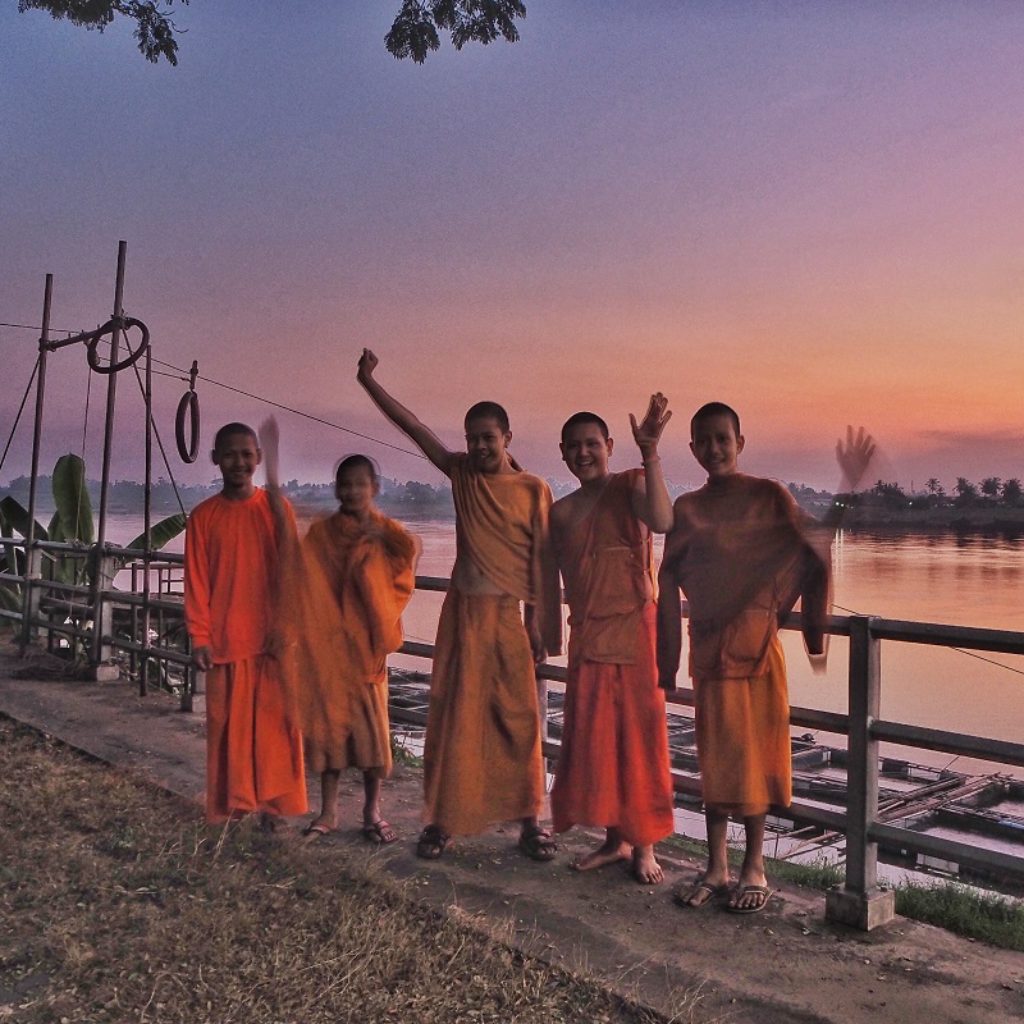 young buddhist monks waving